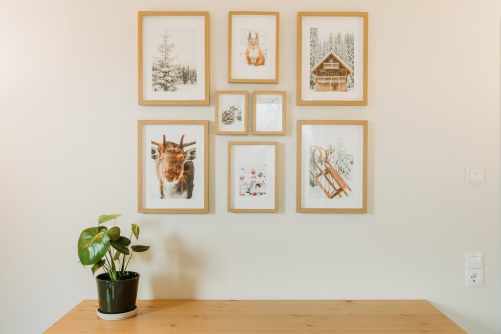 Mit Naturmotiven in Bilderrahmen dekorierte Wand und dekorative Grünpflanze