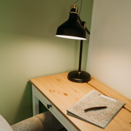 Kleiner Holzschreibtisch mit bequemem Polstersessel und Schreibtischlammpe.